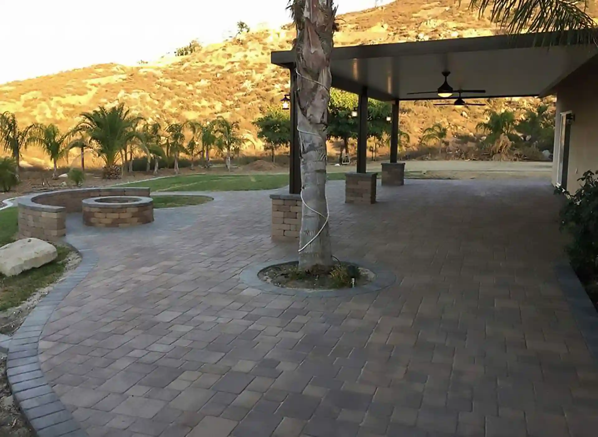Photo of a spacious paver patio featuring a built-in fire pit area. 