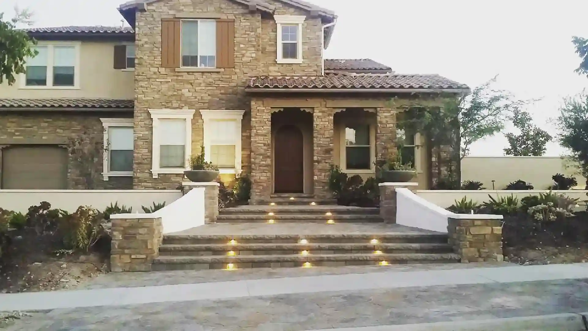 Photo of home entrance featuring stone facade and illuminated front steps that feature low-voltage lighting. 